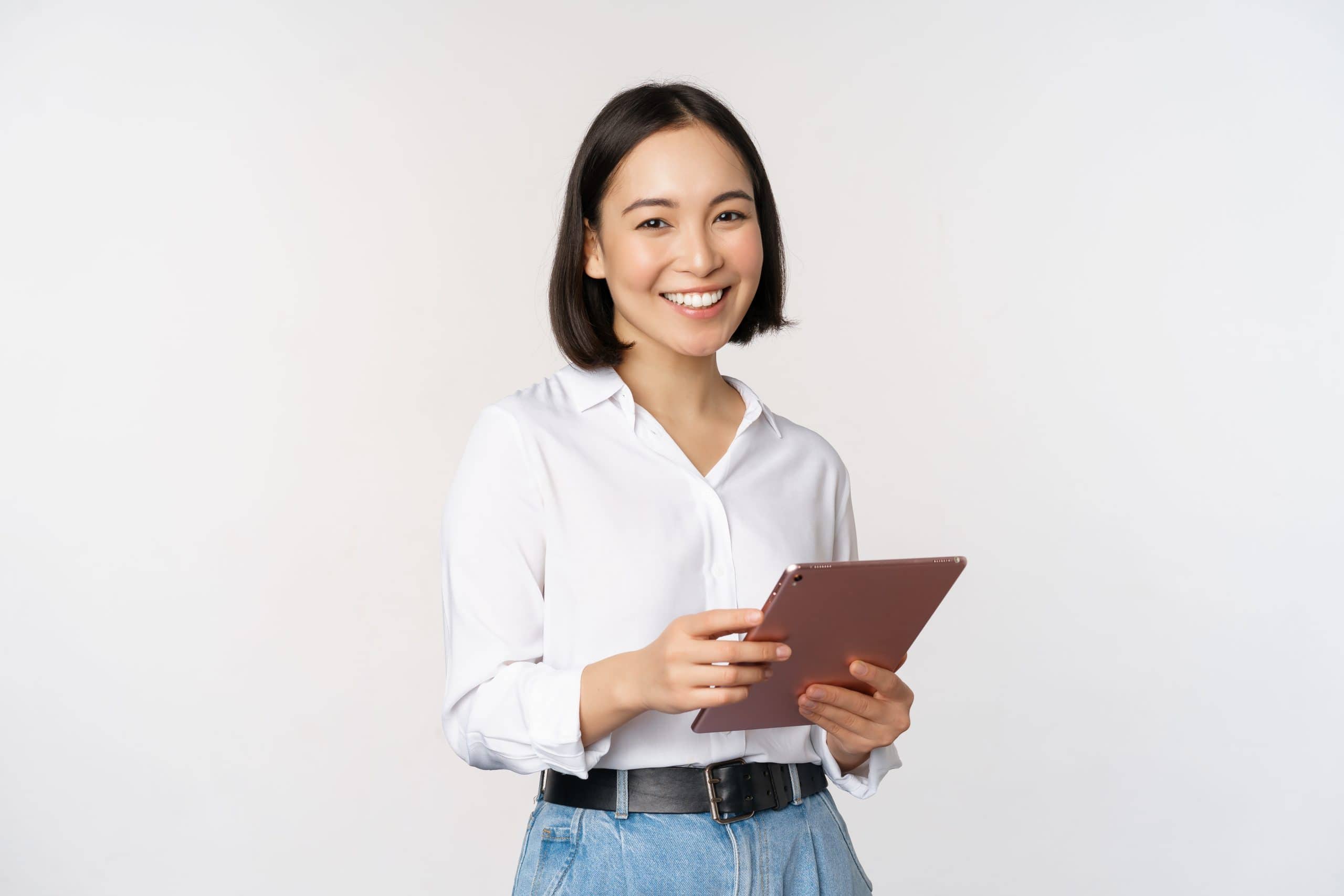 Image of young ceo manager, korean working woman holding tablet and smiling, standing over white background